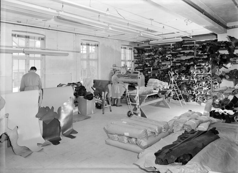 Svart-hvitt foto fra produksjonslokale med skinnruller i Norrøna skofabrikk.