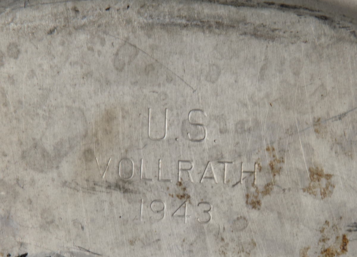 Fältflaska och mätkärl i kanvasfodral. På fodralets framsida står "U.S. stämplat och på baksidan "SHANE MFG. CO 1942" samt påskriften "S.4103".
Inuti fodralet förvaras en fältflaska och ett koktjärl instoppat i varandra.
I botten på fältflaskan står det: "U.S. VOLLRATH 1943" präglat och på handtaget till matkärlet står det "US FOLEY MFG CO 1944".