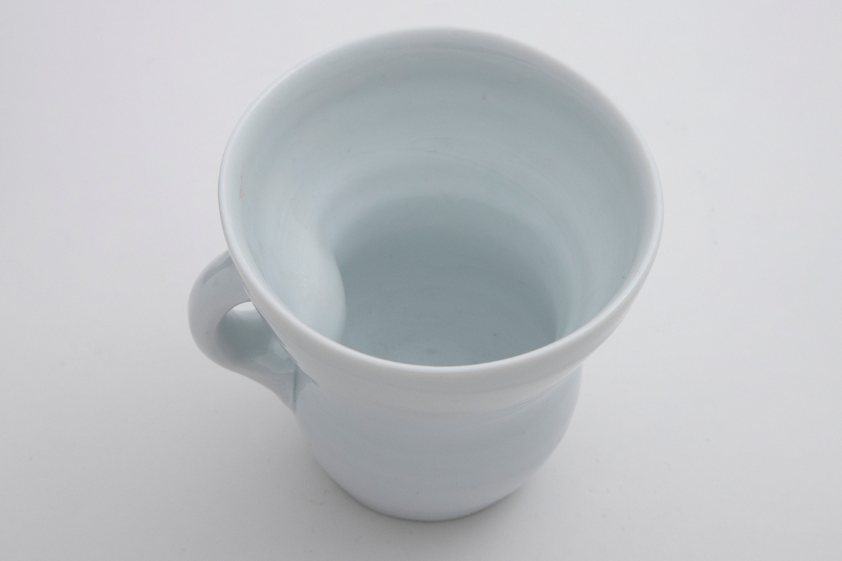 Stor hvit kopp med et hint av lys blå celadon på utsiden og mer synlig celadon på innsiden.
