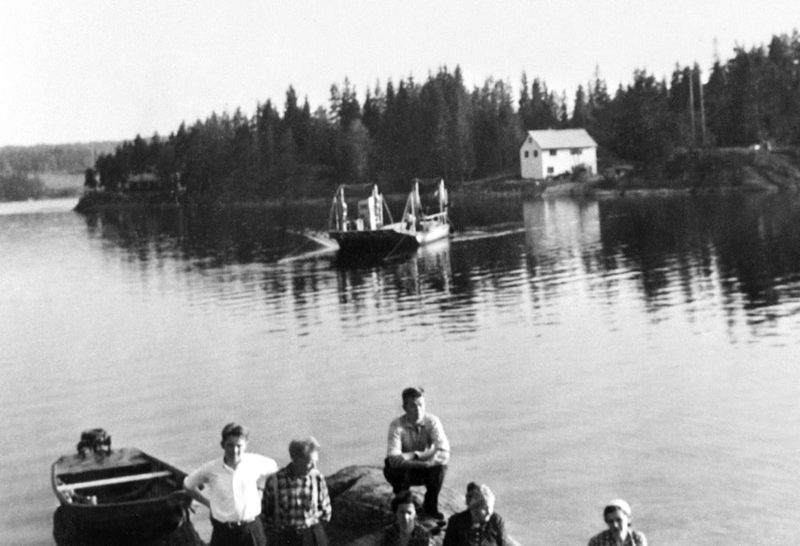 Fergen fra vestsiden av Kroksund nærmer seg fergestedet på østsiden. Området ved liggesletta på vestsiden var skogbevokst nesten helt ned til vannet. Bildet ble tatt i begynnelsen av 1950-årena, akkurat ved den tiden var plassen benyttet av taterne/romanifolket. Foto: Ukjent. Østfold fylkes billedarkiv.