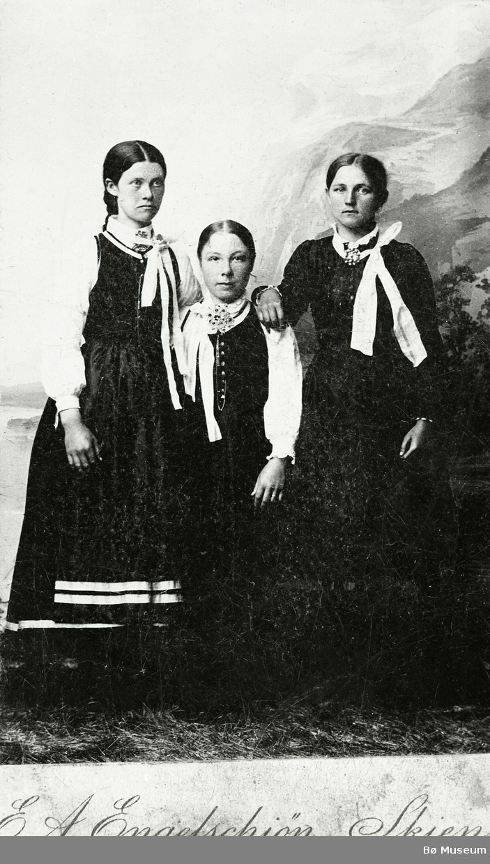 Tre yngre kvinner i vesttelemark-drakt i fotoatelier.
Kvinna t.h. er Liv O. Nørsthaug, gift Tjønntveit i Øvre Bø.
Dei andre er to venninner.