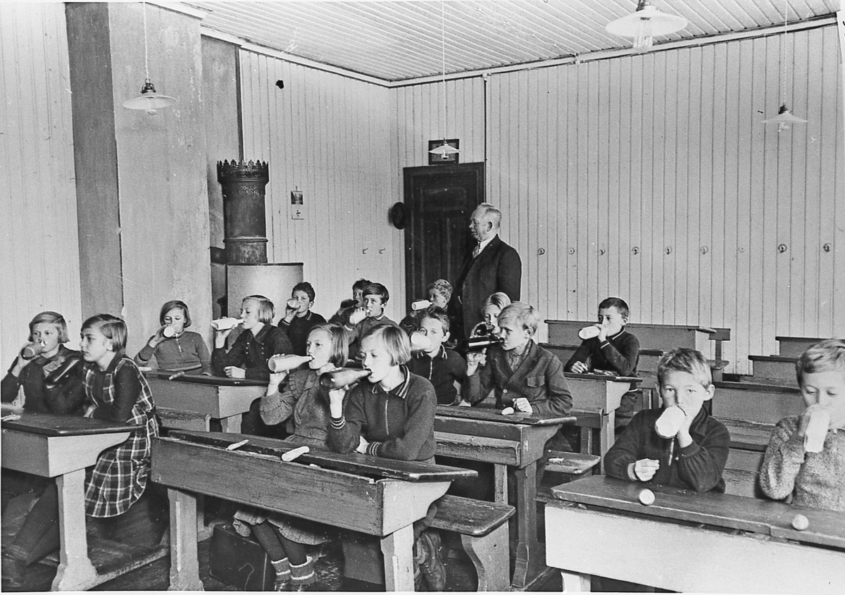 Sigdalsfrokosten demonstreres ved Kringstad (senere Prestfoss) skole, ca. 1935. Etter å ha spist skulle elevene drikke melk. Stående: Lærer Albert Mørch, sittende som nr. 2 fra høyre: Åsmund Aasly.