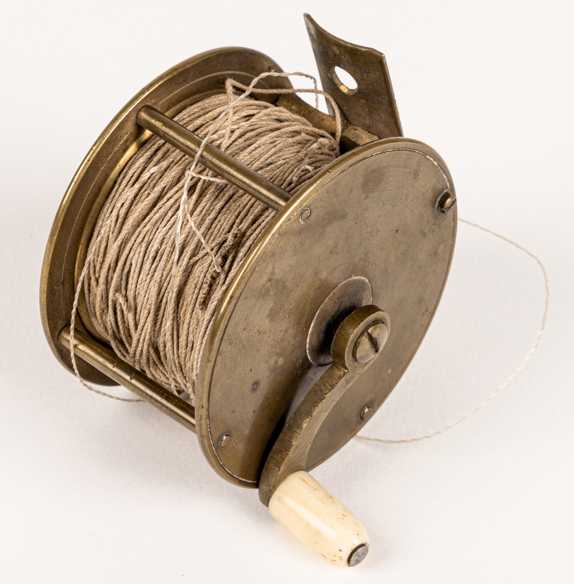 Kastspörulle av mässing. Har använts vid laxfiske. Tvinnad rev av lin. Från 1870-talet.
