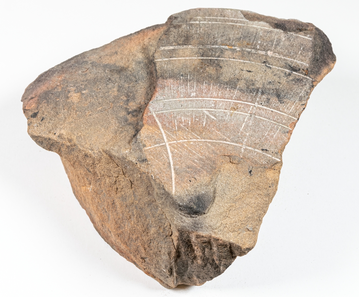 Fragment av slipsten, 7,5 cm tjock, och 16,5 cm bred från mitthålets ytterkant.