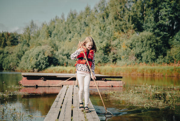 Foto av et barn som prøver å fange insekter i vann ved en flåtegang