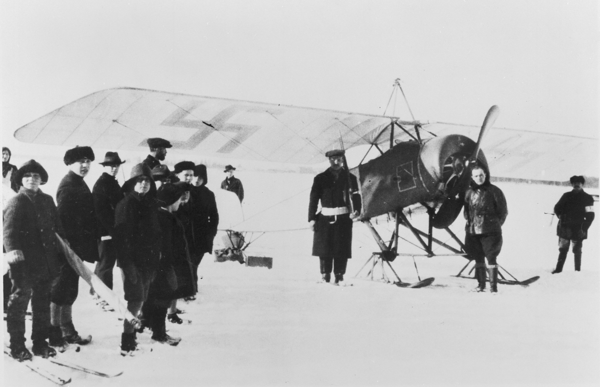 Flygförare Nils Kindberg framför flygplan Thulin D, efter leveransflygning på isen utanför Vasa, 6 mars 1918. Folksamling kring flygplanet.