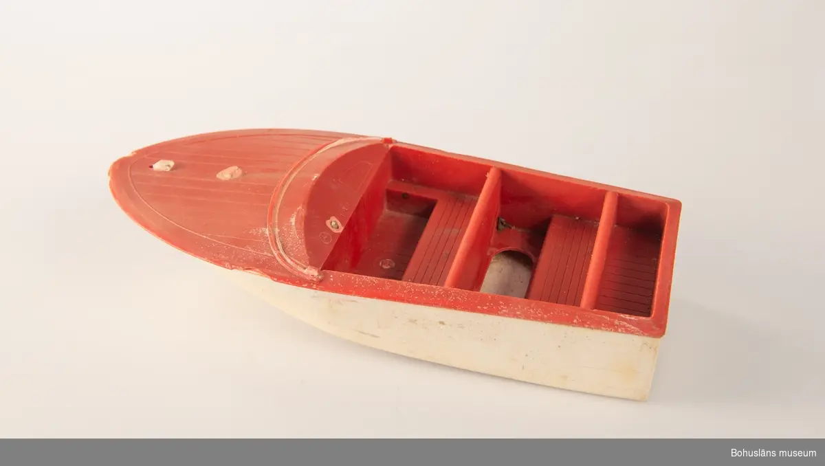 Leksaksbåt, motorbåt med vitt skrov och röd överbyggnad.