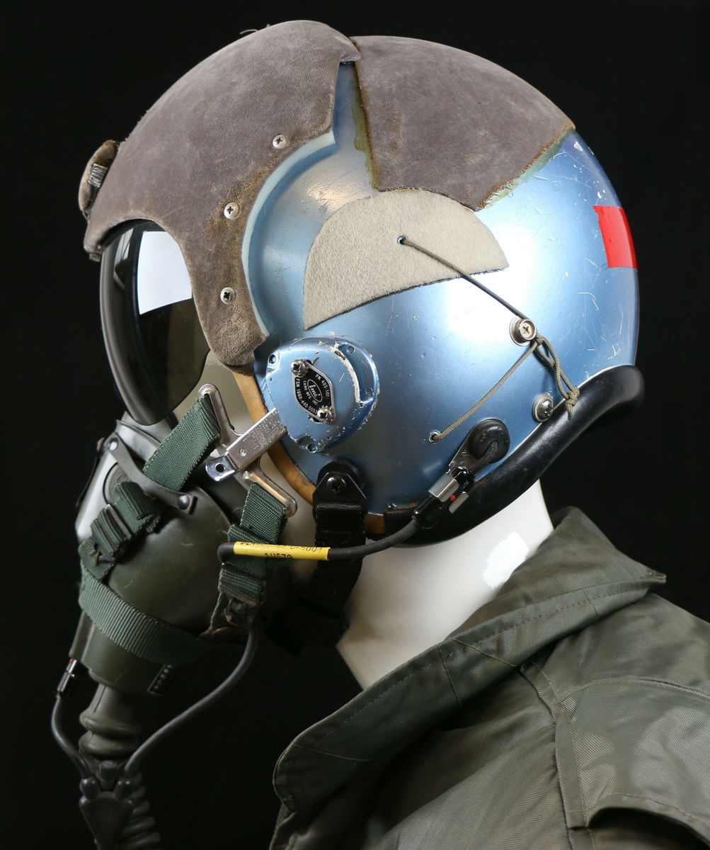 Blå metallic hjelm med grå filt og rødt reflekstape i nakken formet som et + 