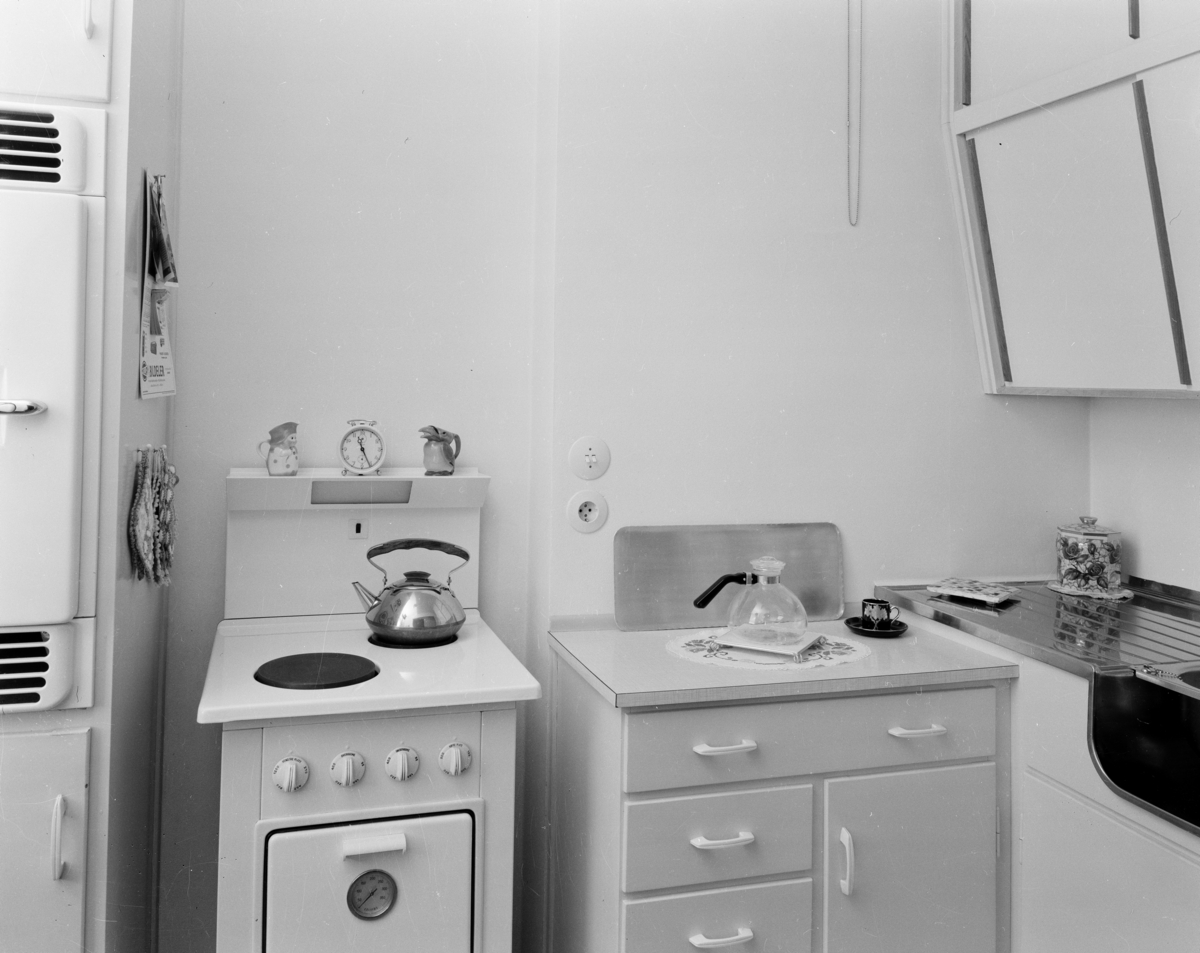 nteriørfoto av et 50-talls kjøkken med skråskap, komfyr og kjøleskap.