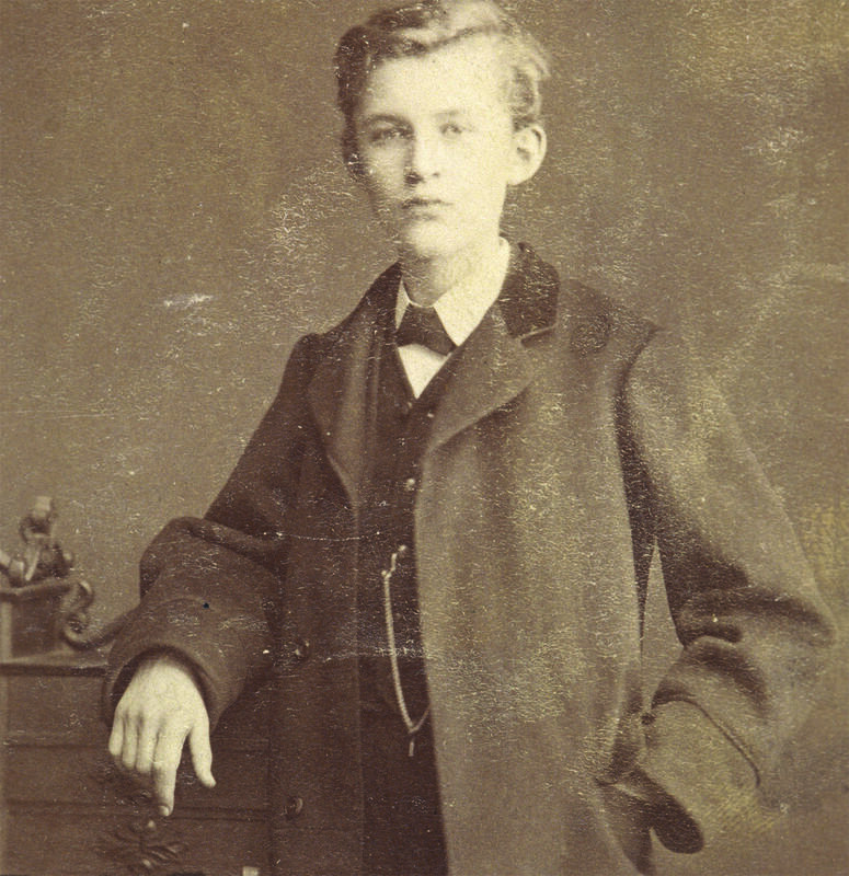 Ung Edvard Munch, står penkledd og lener seg til en kommode