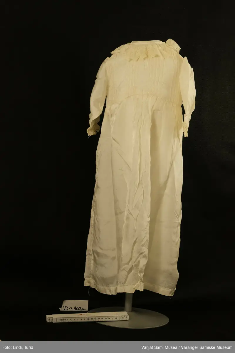 Dåpskjole i blankt stoff/silke med mansjetter og halslinning i heklet bomull.