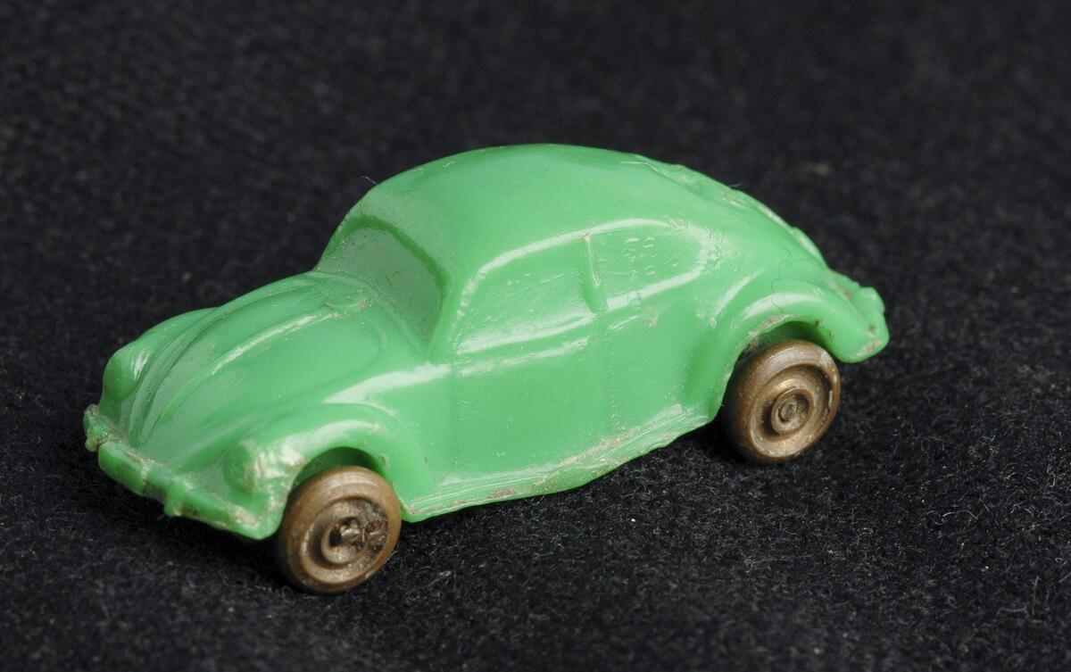 Bilde av grønn lekebil i plast mot sort bakgrunn