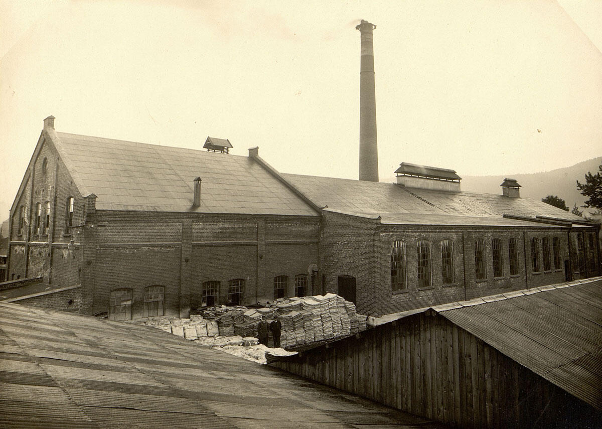 Sort-hvitt bilde av en fabrikkbygning i murstein med en skorstein (Foto/Photo)