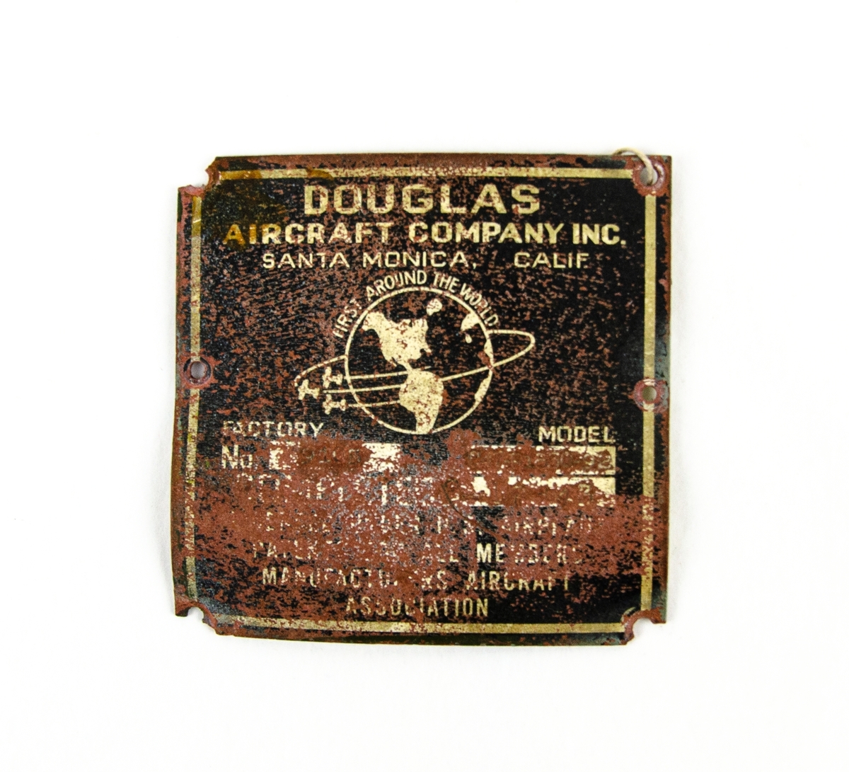 Tillverkningsskylt för flygplan. Svart bakgrund med vitgul text. Skylt och text är nött av tidens tand. Tillverkare är Douglas Aircraft Company, Santa Monica, Kalifornien.
