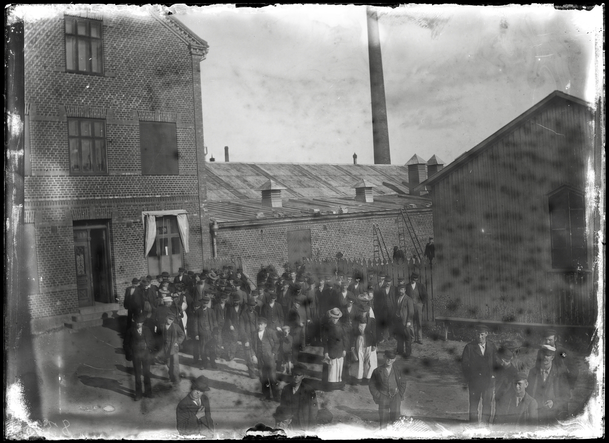 Fabriksarbetare framför fabrik