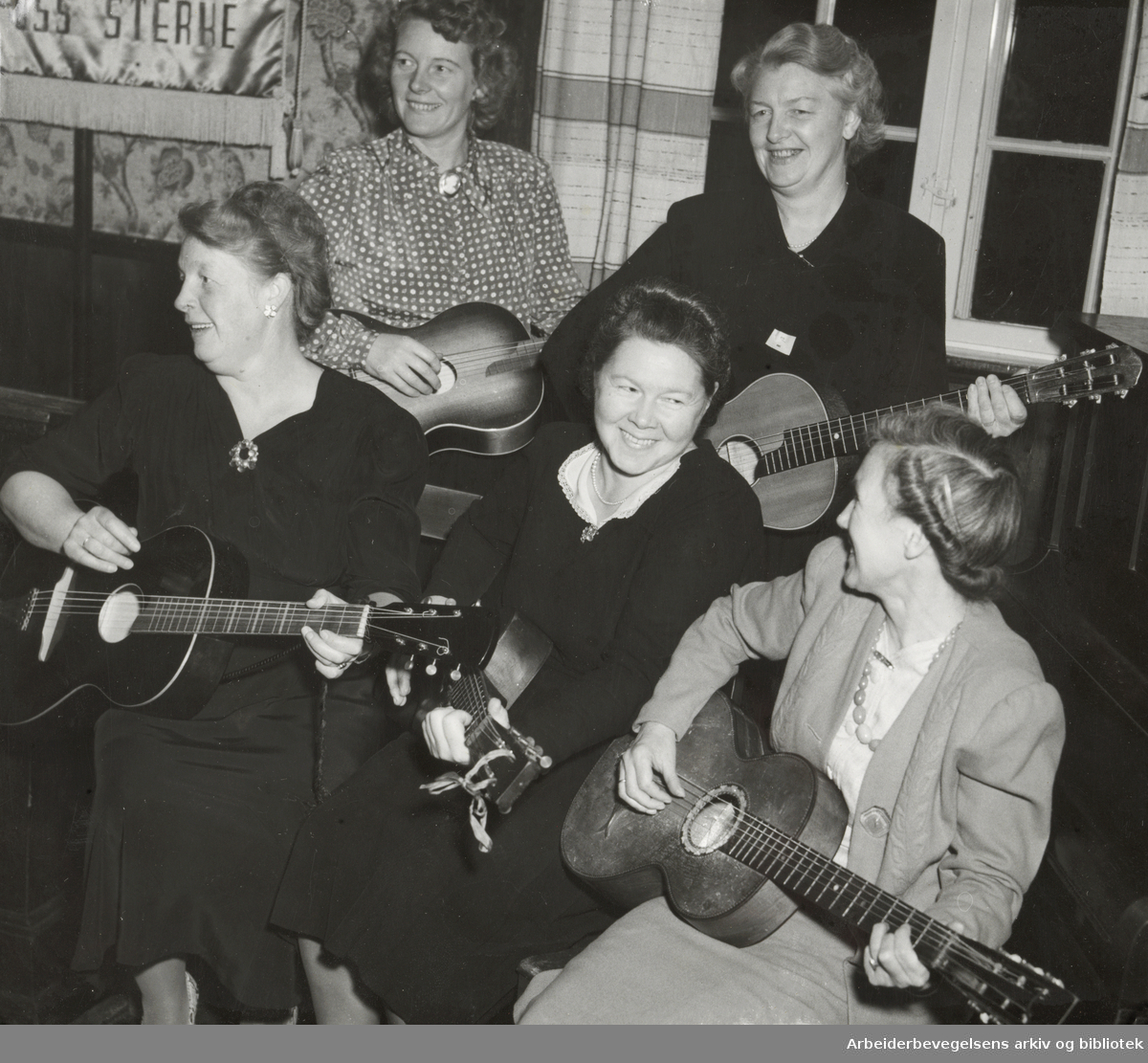 Simensbråten kvinnegruppe av DNA feirer sitt 5-års jubileum med gitarspill. Fra venstre: Margit Gammelsrud, Ågot Johansen, Lydin Jacobsen, Else Pedersen og Magnhild Johansen. November 1950