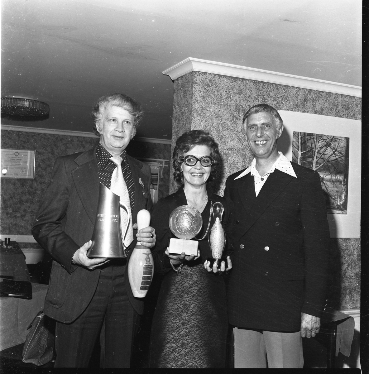 Två män och en kvinna med priser i händerna, bland annat en bowlingkägla.