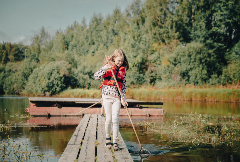 Foto av ei jente som prøver å fange insekter i vann