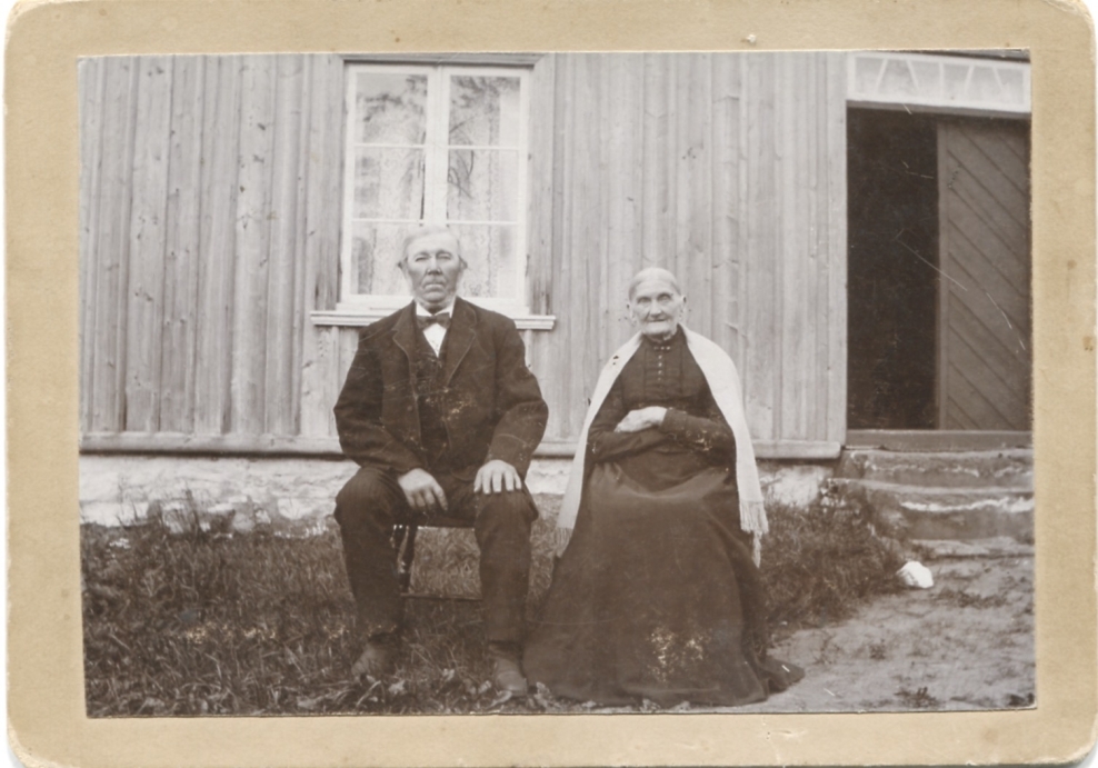 Ett okänt äldre par sitter framför en byggnad, okänt årtal och plats. Eventuellt Hilda Sandbergs fosterföräldrar från Hjärtum eller Anders och Robert Sandbergs släktingar i Lindome. Foto från Sagered-album.