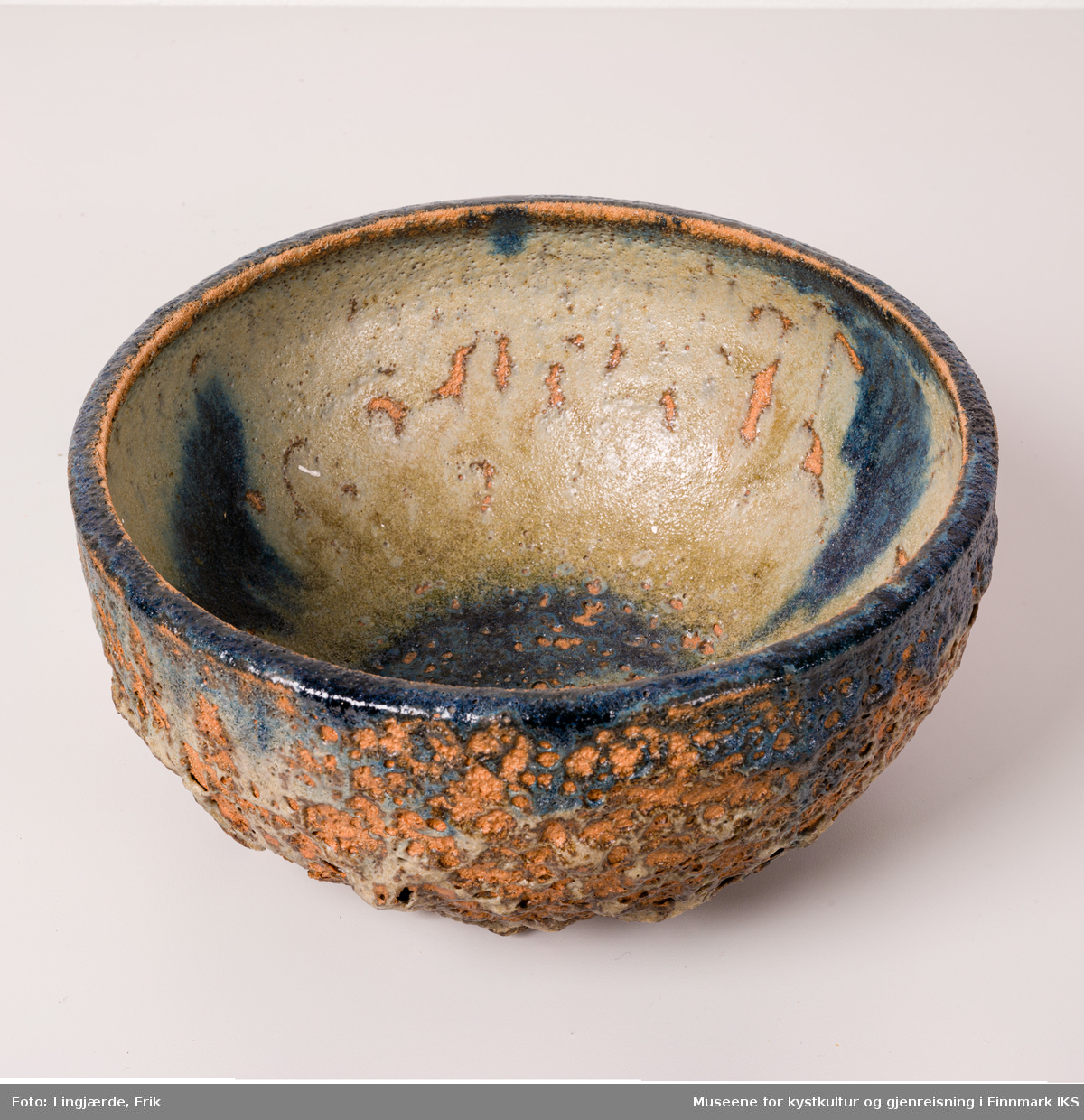 Skålen er utført i keramikk, med en grov, askeglasert overflate, bestående av en miks av jordtoner og forskjellige strukturelementer.