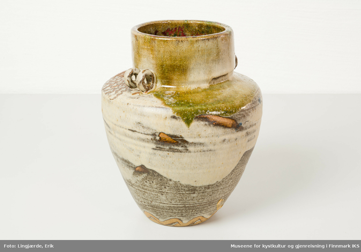 Krukken er utført i askeglasert keramikk. Overflaten består av en miks av jordtoner og forskjellige strukturelementer.