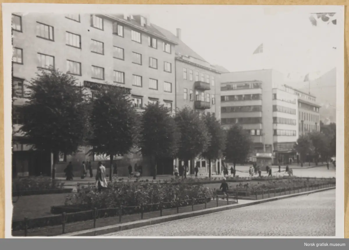 Bymotiv fra Bergen. Forretningsbygg med parkanlegg og trær i forgrunnen. Fotografert i forbindelse med Vestlandsk Trykkerstevne 1946.