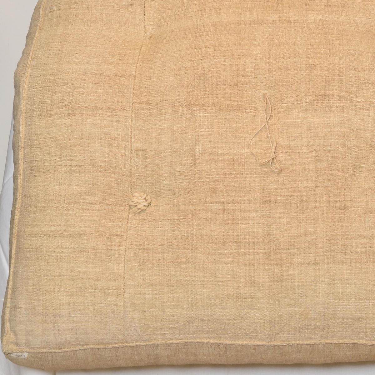 Madrass tillverkad i grov linneväv, med halmstoppning. Med puskor, som på ena sidan är gjorda av vejideblå linnelappar och på andra sidan är gjorda av vitt ylle.