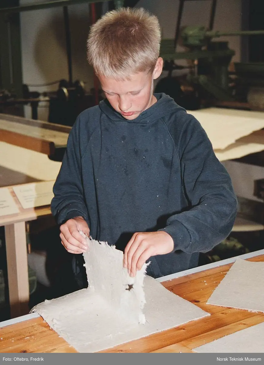 Papirfremstilling i Norsk Teknisk Museums utstilling Skogen som ressurs. Papiret løftes opp fra filten og er klart til å henges opp til tørking