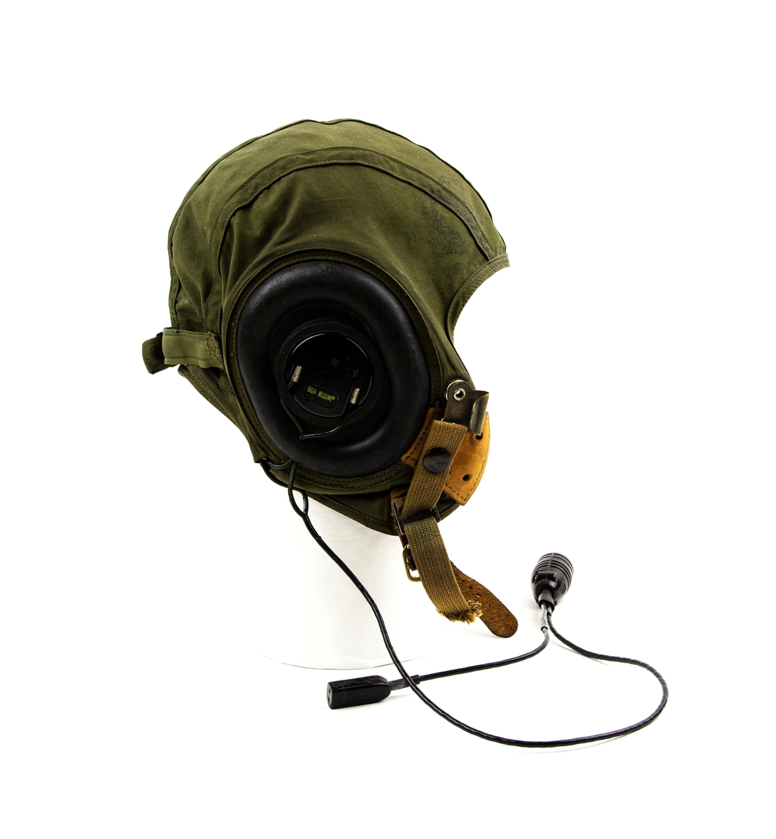 Flyghuva utförd i grönt tyg med gummiskydd för öronen. Med radiomottagare (9824) och kabel. Hakrem i läder som knäpps med spännen. Insida fastsydd blå textiletikett med gul text "MEDIUM".