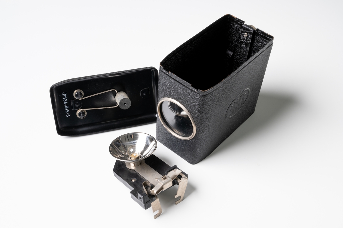 Ficklampa, utrustning inom civilförsvar. Låda med lock av svartlackerad plåt. På locket är ett handtag fäst, och två tryckknappar av plast/bakelit. På ena kortsidan finns ett runt glas. På var långsida av lådan är präglad text: "NIFE". Ett fäste av bakelit med lampa ligger löst, inslaget i beige papper, inne i lådan. Oanvänd. 

Se Historik.