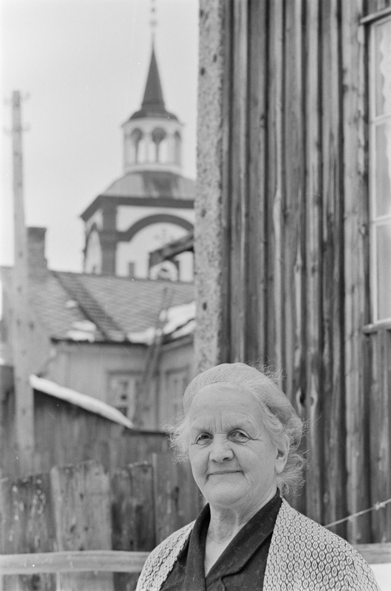 Portrett av en kvinne med Røros kirke i bakgrunnen.