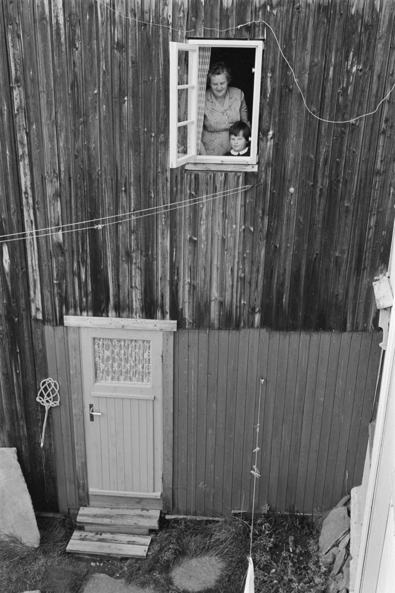 En kvinne og et barn står i et vindu på Røros.