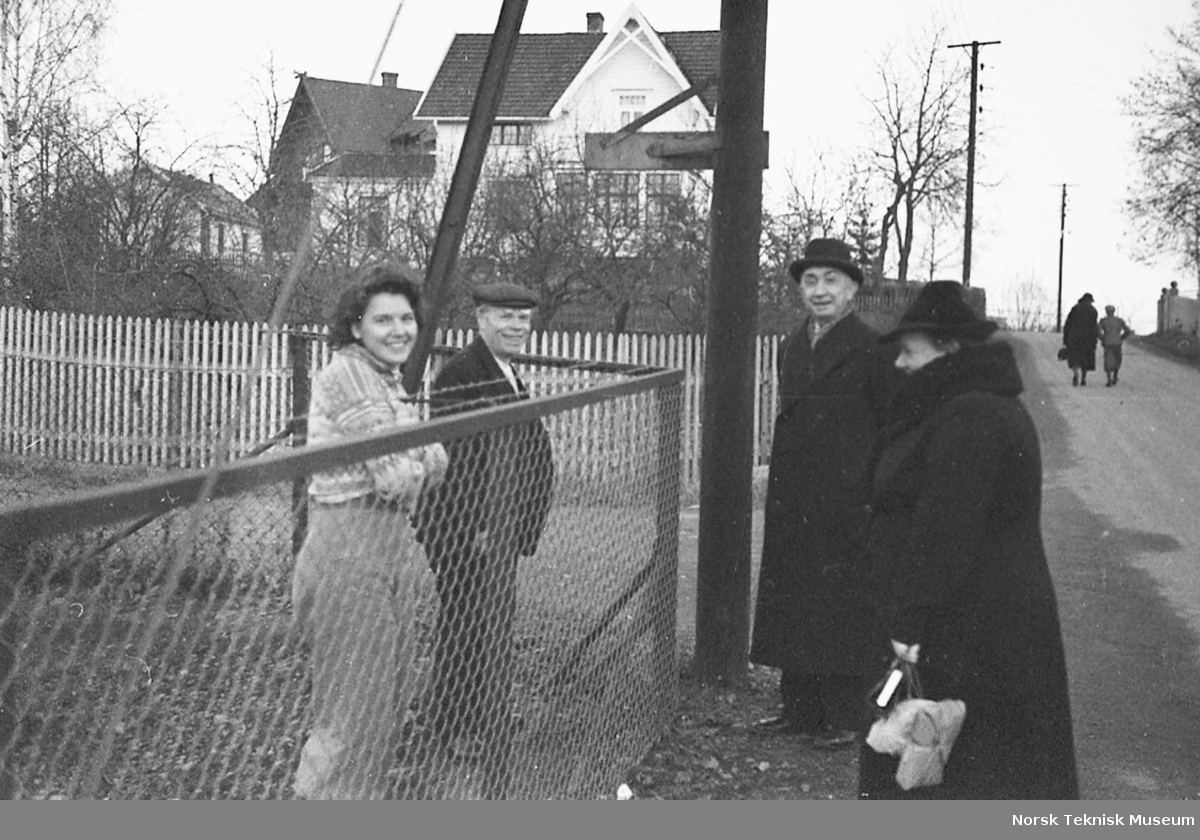 Hans Halvorsen og svigerdatteren Annie prater over gjerdet med Annies foreldre Marie og Bertrand Danielsen i Hasleveien utenfor Halvorsens Verksted, våren 1940