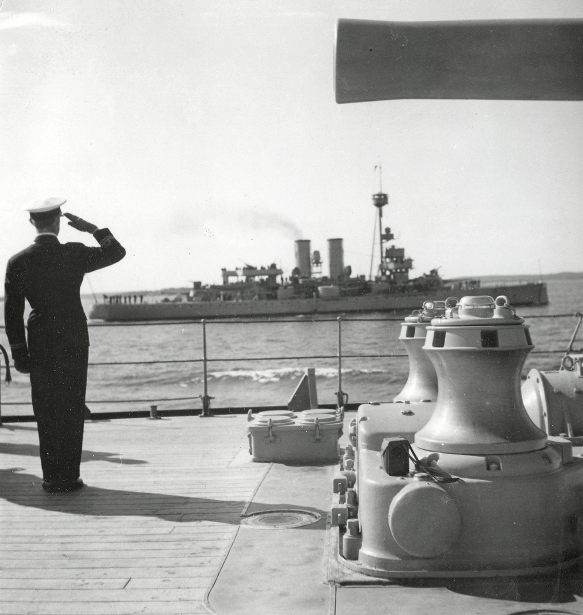 Pansarskeppet ÄRAN. I förgrunden gör ett befäl honnör på däck på ett pansarskepp av SVERIGE-klass.