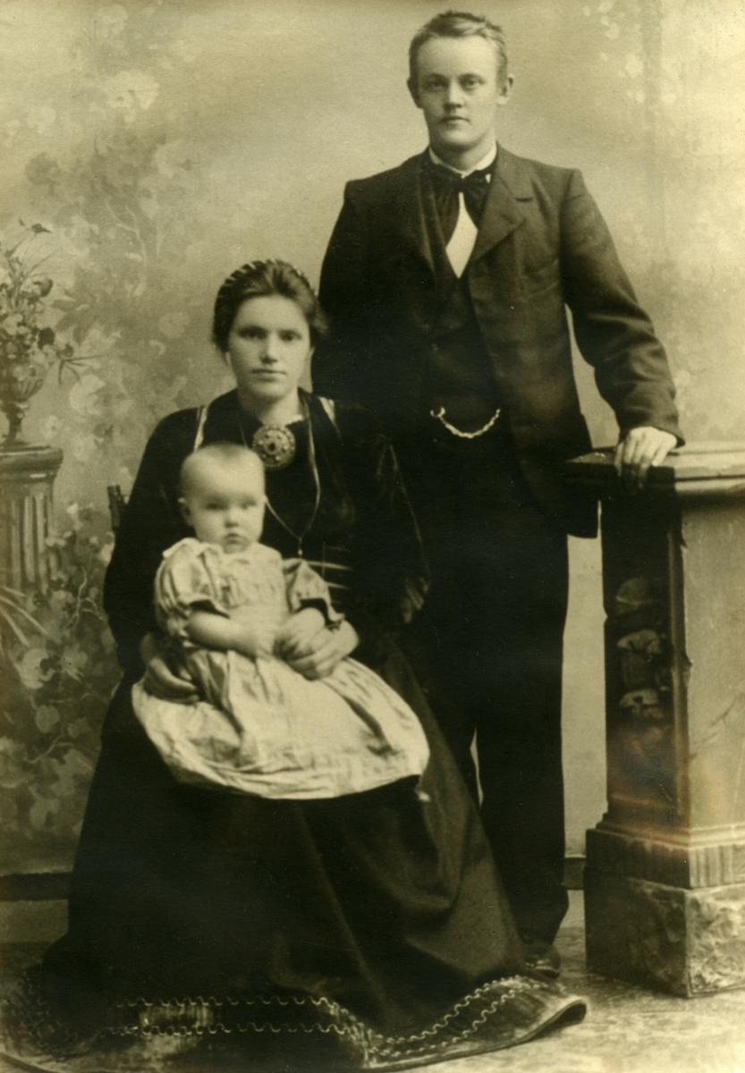 Visittkortfoto av Erik og Torbjørg Helland med eit barn, truleg den eldste dottera, fødd 1902.
