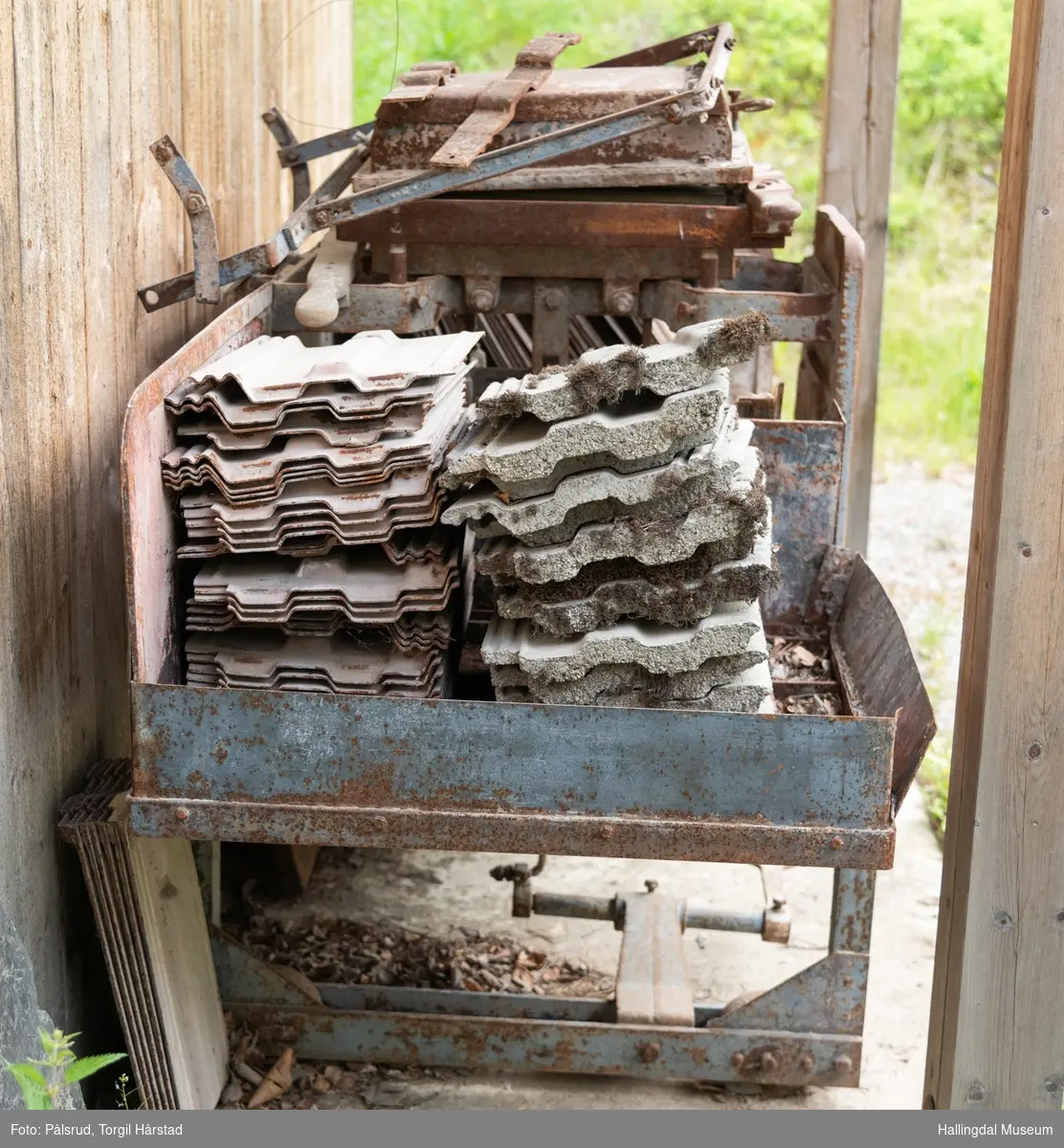 Taksteinspresse i støpt jern med takstein og støpeformer. Til å presse (støpe) takstein. Har vært i bruk på gården Østenfor, Nesbyen.