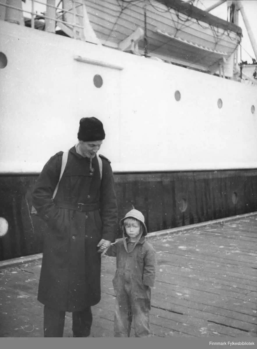 Sivilingeniør Nils E. Hertzberg med sønnen Kristian på Vadsø D/S kai. Bak dem ser man noe av en båt, kanskje hurtigruta.