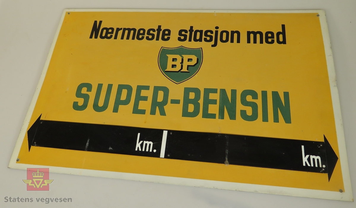 Rektangulært reklameskilt av 1 mm tykk aluminiumsplate, lakkert, med teksten "Nærmeste stasjon med BP SUPER-BENSIN km km", i svart, hvitt og grønt på gul bunn. Skiltet har 4 hull for fastsetting. Ubehandlet bakside. Ser ut til å være ubrukt.