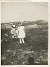 Två syskon står på en äng och håller varandra i handen, Heljered Sörgård 2:3 "ordförans" cirka 1920. Från vänster: Åke Johansson (1918 - 1987) och Sonja Johansson (1912 - 1997), barn till Selma och Carl Johansson.