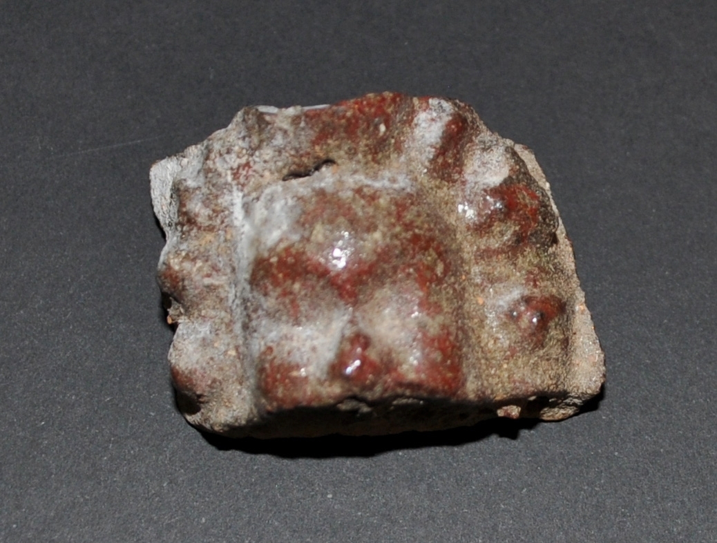 Fragment av kakelugn som föreställer en del av ett ansikte med näsa och lockigt hår. Skall komma från Visingsborgsslott, grevens gemak i södra flygeln.