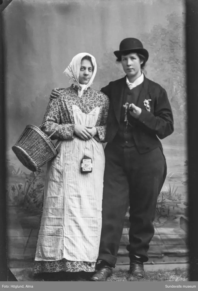Ateljéporträtt av två unga kvinnor, den ena klädd som en man.