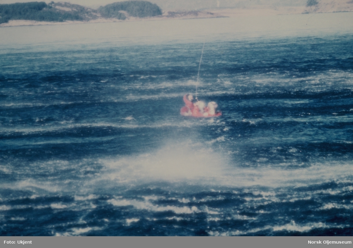 En livredder fires ned fra et helikopter til menn i overlevelsesdrakter i sjøen. På bilde 2 fester han et belte rundt mannen i sjøen og på det siste bildet heises de opp av sjøen.