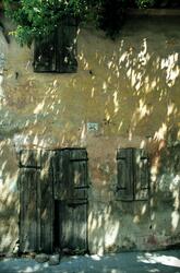 Foto av en vegg med dører og vinduer lukket med lemmer. Sola