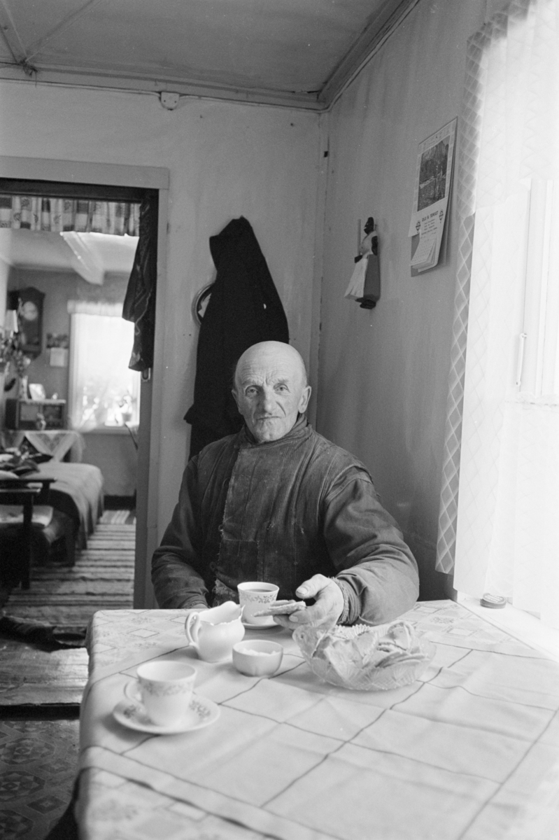 Portrett av en mann sittende ved et bord dekket til kaffe.
