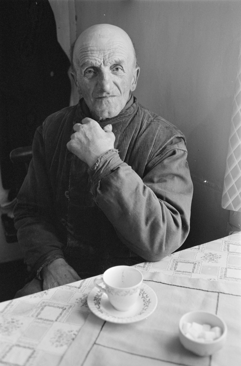 Portrett av en mann sittende ved et bord dekket til kaffe.