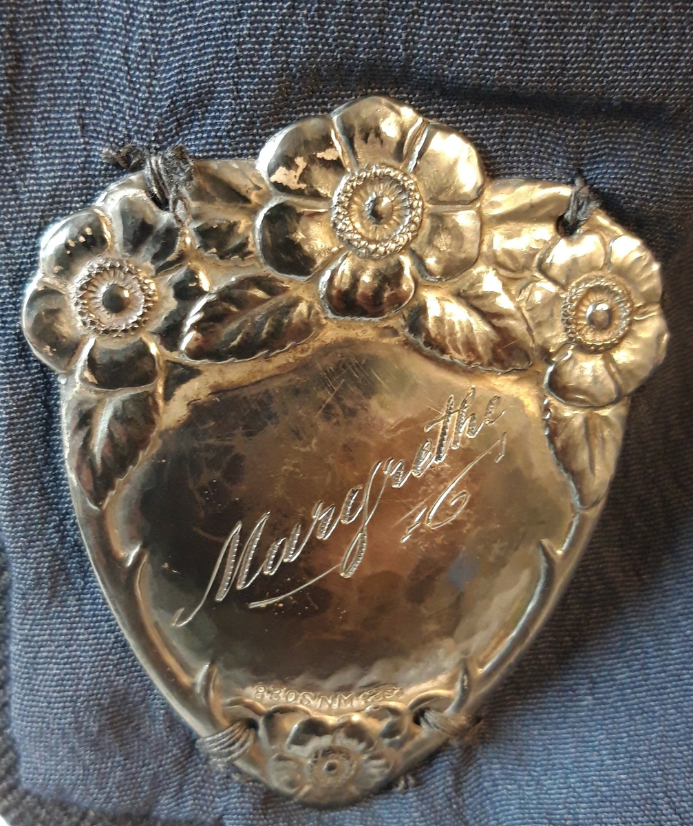 Jakka har påsydd et identitetsmerke på innsiden av høyre side i sølv med navnet Margrethe inngravert.