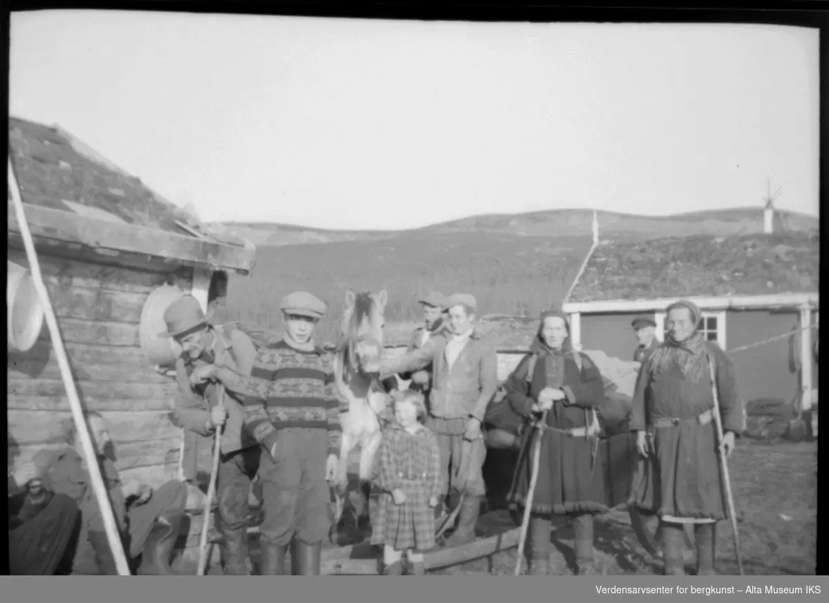 Bilde av flere menn og kvinner i alle aldre på Joatka fjellstue med hest og vogn. Personene som er navngitt på bildet er: Kristian, Mollis-Julius, Klemet, Sofie, Julius, Per, Siri, Oskar, Inga.