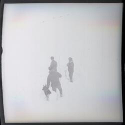 Fotografi av tre menn kledd i vinterklær som står i snøen på