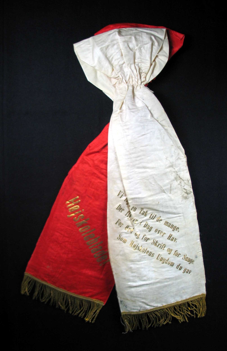Begravelsessløyfe i hvit og rød silke med gullfrynser.