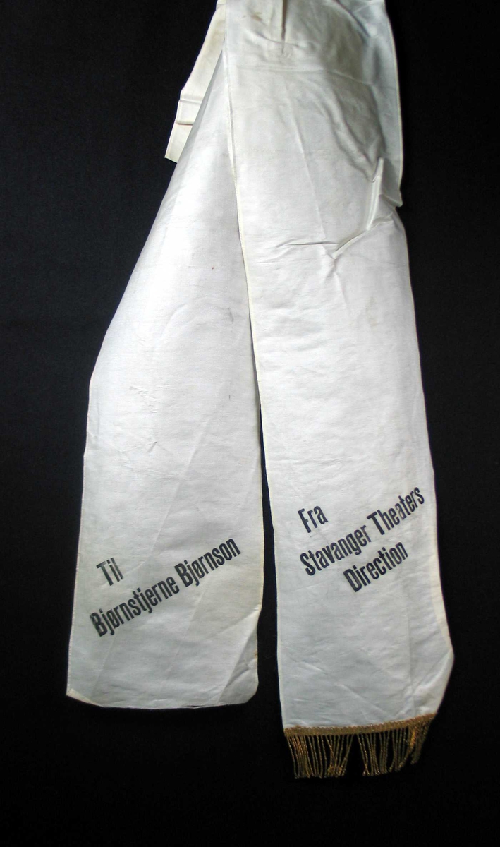 Begravelsessløyfe i hvit silke med svart tekst.